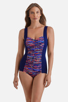 Woman wearing a blue one-piece swimsuit with a multicolor print in the middle