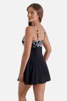 Woman turned left wearing a black and white palm tree printed swim dress