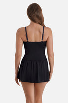 Woman turned away wearing a black, blue and white floral printed skater swim dress with black skirted bottom