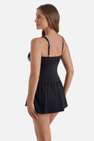 Woman turned left wearing a black, blue and white floral printed skater swim dress with black skirted bottom