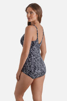 Woman turned left wearing a black and white dot printed one-piece swimsuit
