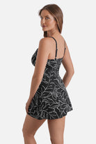 Woman turned left wearing a black and white floral outline printed swim dress