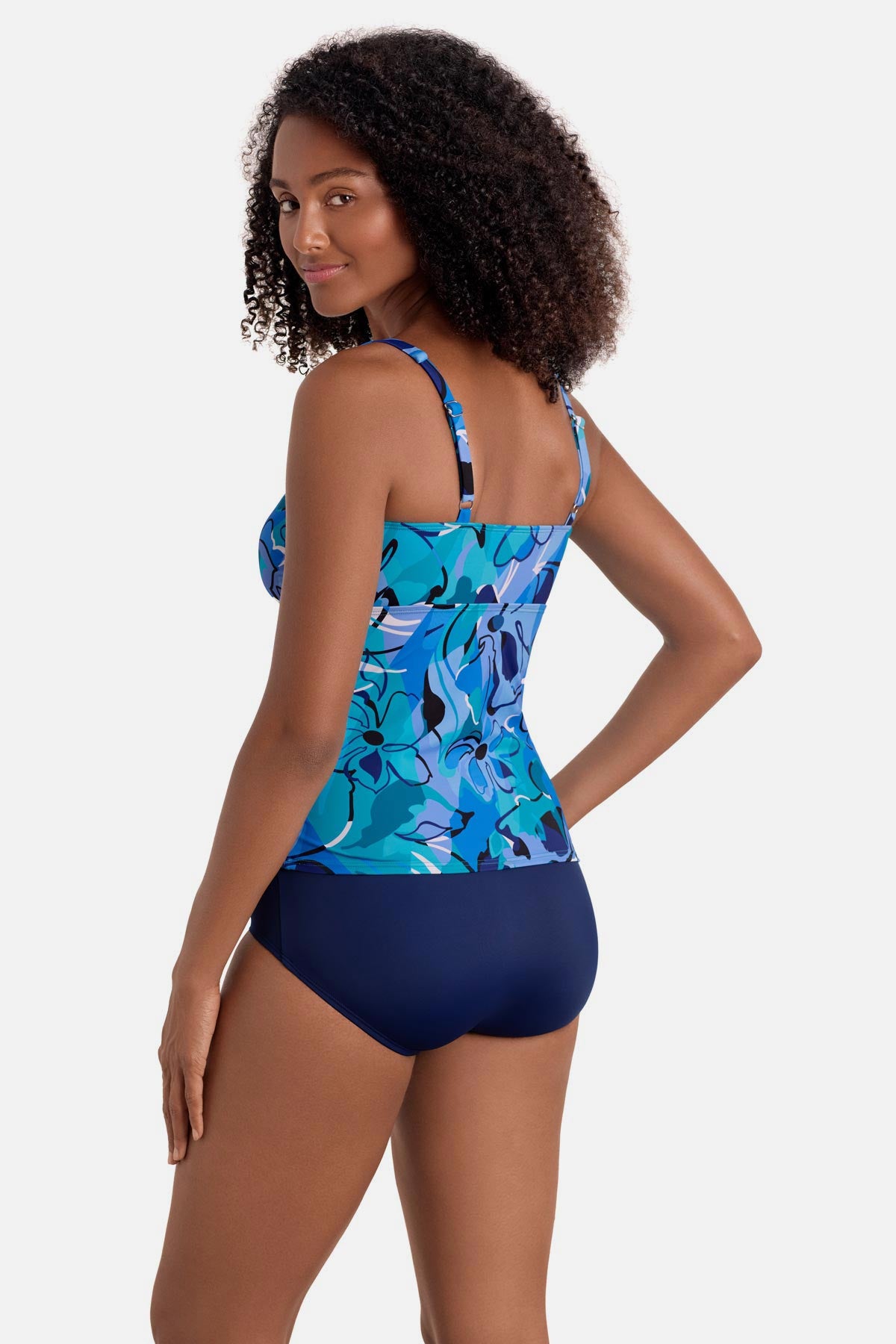 Woman turned left wearing a blue floral printed shirred tankini top