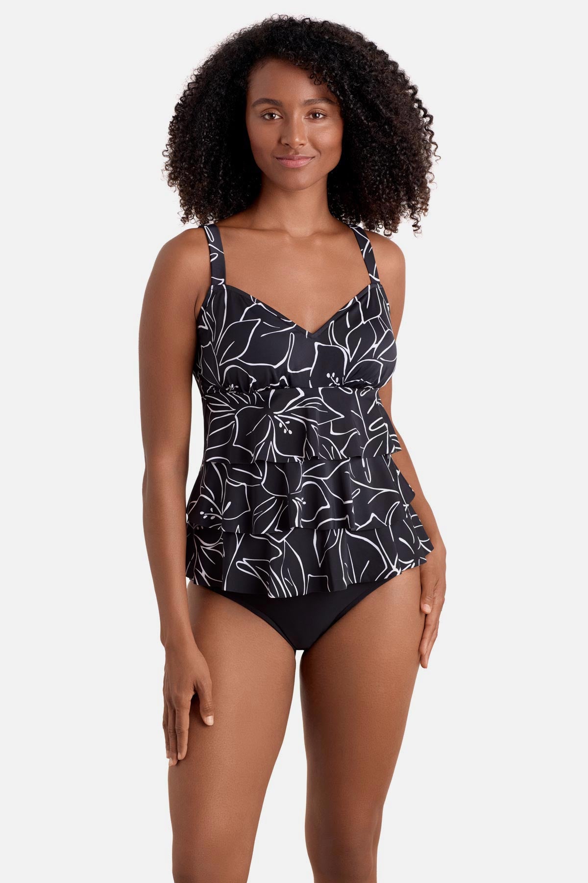 Woman wearing a black and white floral outline print tankini top with ruffles