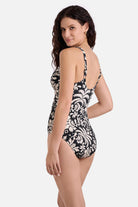 Woman turned left wearing a black and white palm tree printed one-piece swimsuit
