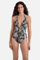 Woman wearing a black and white palm tree printed deep v-neck one-piece swimsuit