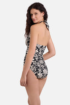 Woman turned left wearing a black and white palm tree printed one-piece swimsuit