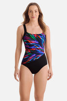 Woman wearing an electric rainbow printed one-piece swimsuit