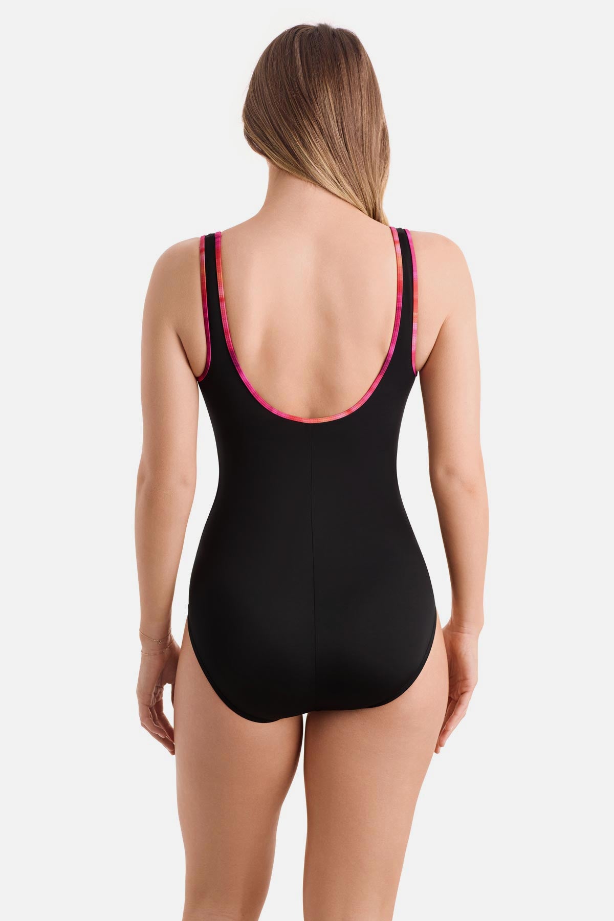 Woman turned away wearing a black one-piece swimsuit with pink piping on the edges
