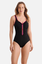 Woman wearing a black one-piece swimsuit with pink piping on the edges