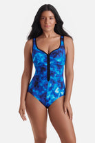 Woman wearing a black and blue cloud printed one-piece swimsuit with a zipper down the front