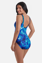 Woman turned left wearing a black and blue cloud printed one-piece swimsuit with a zipper down the front