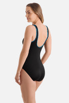 Woman turned left wearing a black one-piece swimsuit with a blue braided piping on the edges