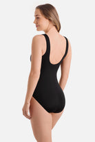 Woman turned left wearing a black and white maze print one-piece swimsuit with a zipper down the front