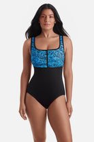 Woman wearing a black and blue abstract printed one-piece swimsuit with a zipper down the front