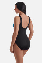 Woman turned left wearing a black and blue abstract printed one-piece swimsuit with a zipper down the front