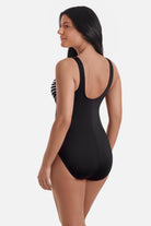 Woman turned left wearing a black and white abstract pattern one-piece swimsuit