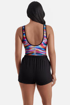 Woman turned away wearing a rainbow tie dye one-piece swim romper