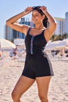Woman on beach wearing a one-piece romper swimsuit with rainbow piping