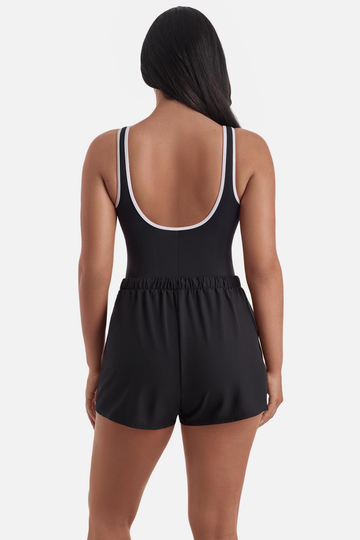 Woman turned away wearing a black and white one-piece swim romper