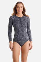 Woman wearing a long sleeve one-piece swimsuit with a black and white abstract print
