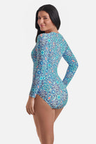Woman turned left wearing a long sleeve one-piece swimsuit with a blue tile print