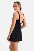 Woman turned left wearing a black and white swim dress with stripes down the sides