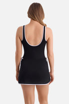 Woman turned away wearing a black swim dress with white piping/edges