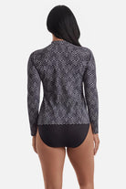 Woman turned away wearing a black and white maze pattern sunshirt