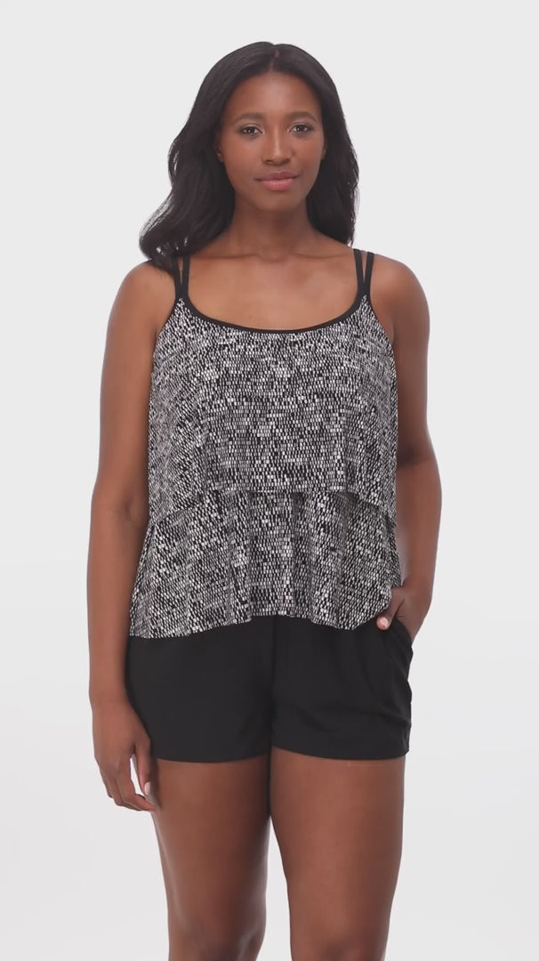 Woman wearing a black and white static pattern ruffle skirtini swimsuit