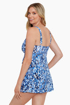 Woman turned left wearing a blue and white abstract printed triple tiered swim dress