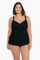 Woman wearing a black ruffled faux tankini one-piece swimsuit with a faint animal print pattern