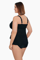 Woman wearing a black ruffled faux tankini one-piece swimsuit with a faint animal print pattern