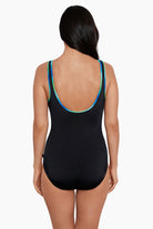 Woman faced away wearing a black one-piece swimsuit with blue and green piping on the straps
