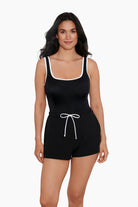 Woman wearing a black swim romper with white piping on the edges